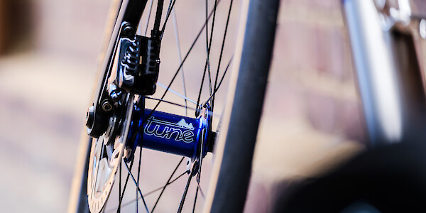 A blue Tune hub laced into a carbon bicycle wheel