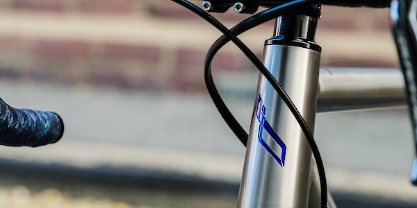 Close-up of a custom-painted headtube logo on a titanium Bossi Summit bicycle