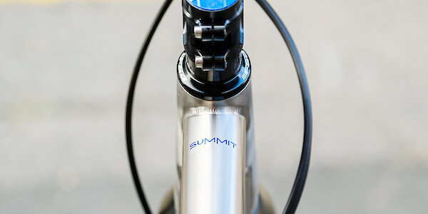 Close-up of a custom-painted frame decal on the top tube of a titanium Bossi Summit bicycle