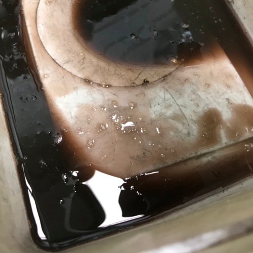 Contaminated fork oil in the bottom of a container during a service