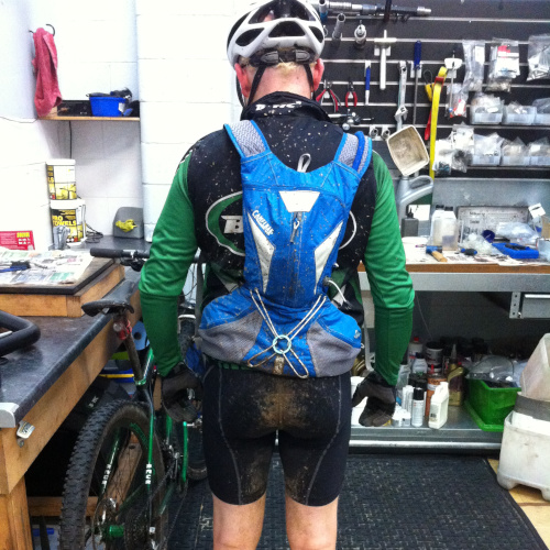 Pete from Bio-Mechanics Cycles & Repairs, shown from behind, covered in mud after a winter mountain bike ride