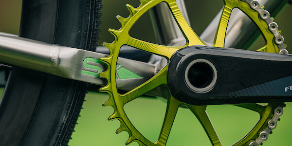 Close-up of a green Garbaruk chain ring fitted to a titanium gravel bicycle