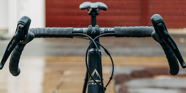 A Fuji Jari 1.3 Carbon gravel bicycle, viewed from the front at handlebar level, against a wet concrete background