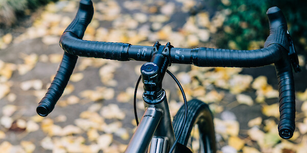Flared gravel handlebars, viewed at an angle, on a Bossi Grit SX titanium bicycle. Yellow leaves litter the background.