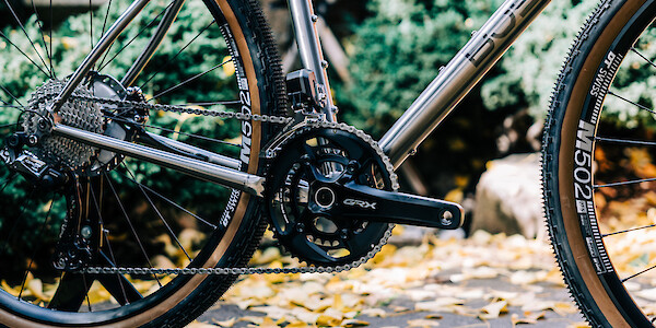 Gear detail on a Bossi Grit SX titanium bicycle, set against a backdrop of green and yellow leaves