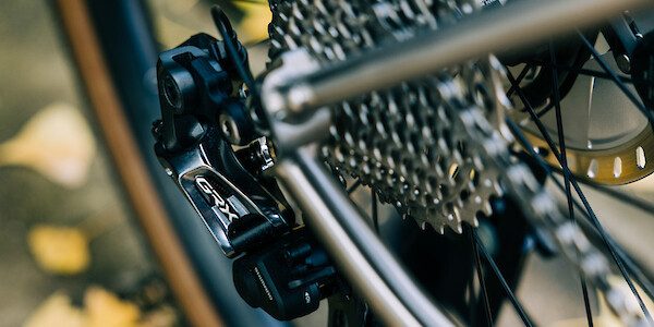 Shimano GRX rear derailleur and cassette detail on a titanium bicycle frame, viewed from above