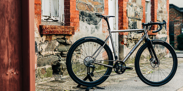 Bossi Grit SX titanium bicycle in a custom build, against an old stone and brick house