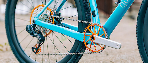Drivetrain detail of Garbaruk bicycle components in orange, fitted to a carbon Gothic Cycles gravel bike