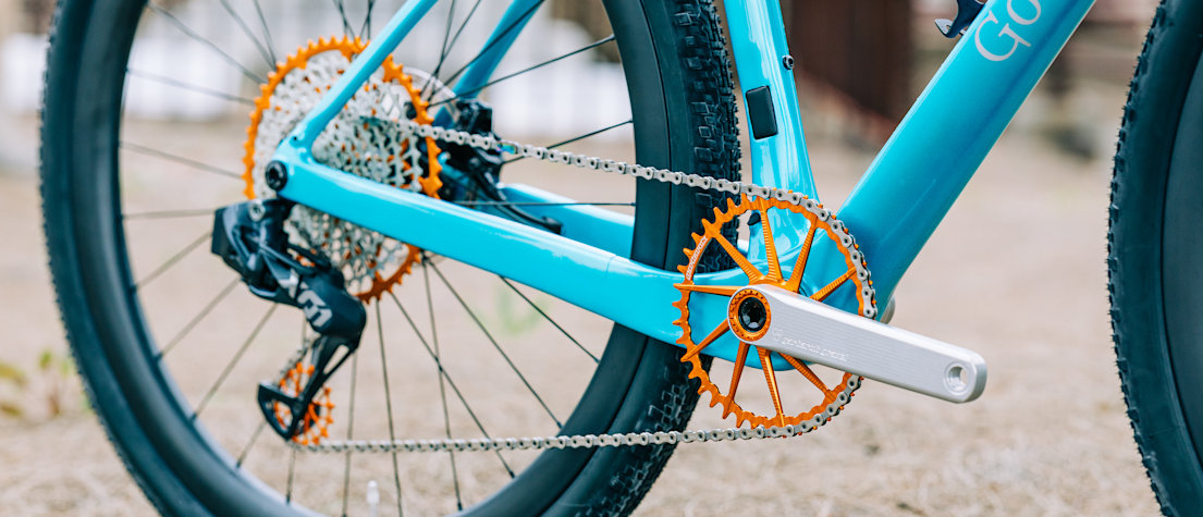 Drivetrain detail of Garbaruk bicycle components in orange, fitted to a carbon Gothic Cycles gravel bike