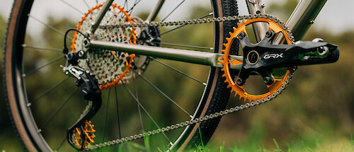 Drivetrain detail of orange Garbaruk bicycle components fitted to a titanium gravel bike