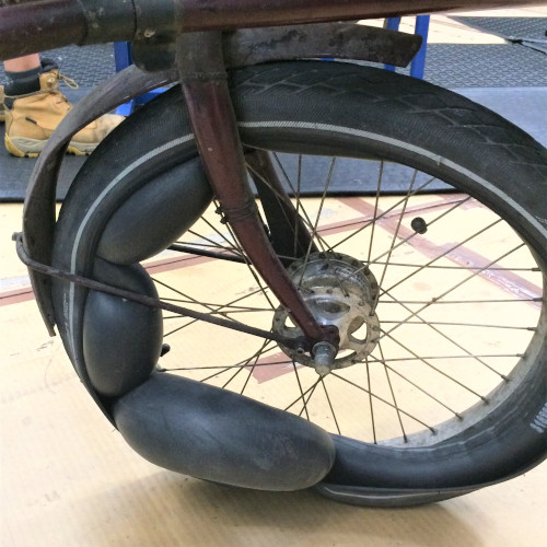 A bicycle tube bulging out of a wheel in sections, like a string of black rubber sausages