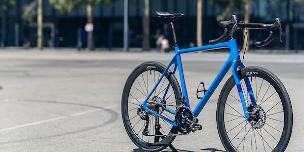 A custom-built Open Cycles U.P. carbon bicycle, against a wide empty concrete expanse