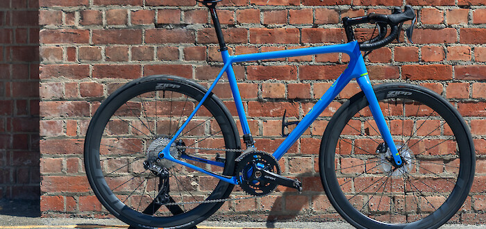 A custom-built Open Cycles U.P. carbon bike against a red brick wall