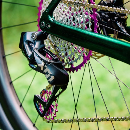 An violet Garbaruk cassette and rear derailleur pulleys, fitted to a green carbon Gothic Cycles gravel bike