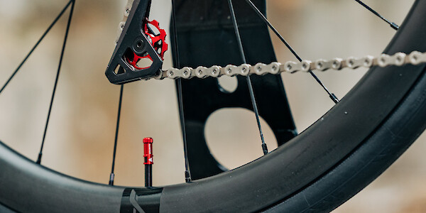Close-up detail on a Garbaruk red jockey wheel and matching red valve cap on a Bossi Strada titanium bike