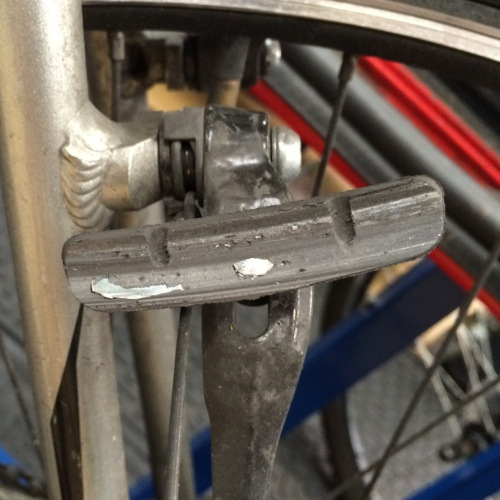 Close-up of a very worn bicycle rim brake pad with the metal backing plate showing through the rubber