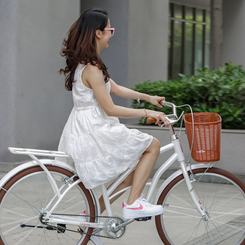 A woman in a white dress riding a white step-through bicycle with a basket on the front