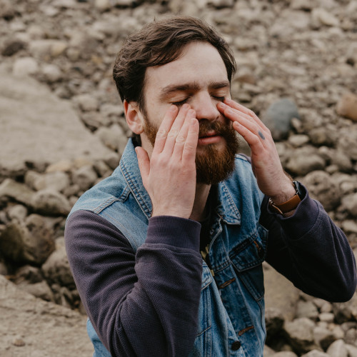 A bearded young man rubbing his face, kind of like the international boyband hand signal for 'crying'.