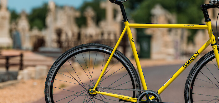 Custom-built Surly Steamroller bicycle in Banana Candy yellow, against a sunny graveyard backdrop