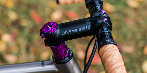 Headstem and handlebar detail on a Bossi Grit titanium gravel bike showing the contrast of the tan and purple components