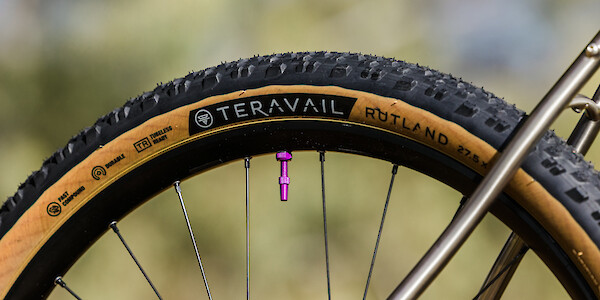 Side detail of a rear wheel with a tan Teravail tyre and purple valve stem, fitted to a Bossi Grit SX gravel bike