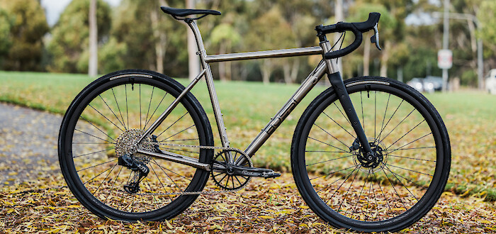 A custom-built Bossi Grit SX titanium bicycle in a leaf-strewn city park