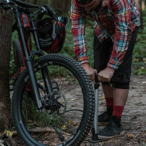 A mountain biker inflating his tyres in a moody forest.