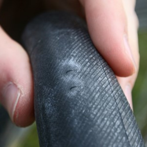 A bicycle tube with snake-bite marks (two parallel lines) indicating a pinch flat