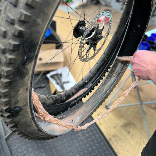 Removing dried tubeless tyre sealant from a mountain bike tyre at Bio-Mechanics Cycles & Repairs. It kind of looks like snakeskin.