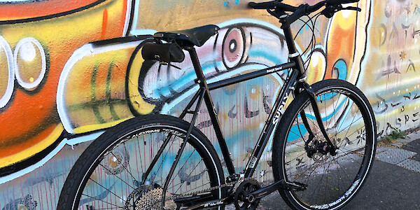 A custom-built Surly Midnight Special bike leaning against a wall of street art