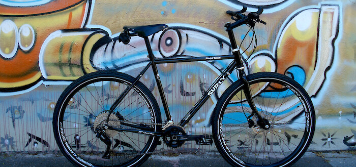 Custom-built Surly Midnight Special bike leaning against a wall of street art