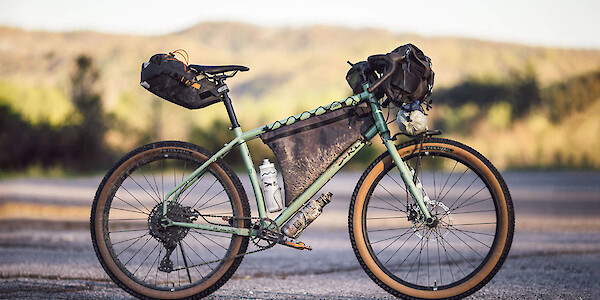 A Surly Grappler bike in Sage Green, fully loaded for bikepacking
