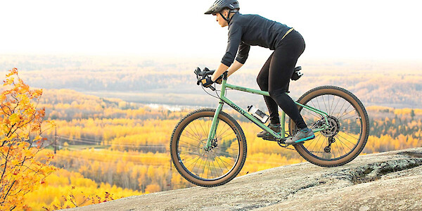 A cyclist riding a Surly Grappler bike down a rock surface