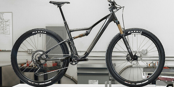 An Ibis Exie USA mountain bike in Clear Charcoal, standing on a table in a workshop