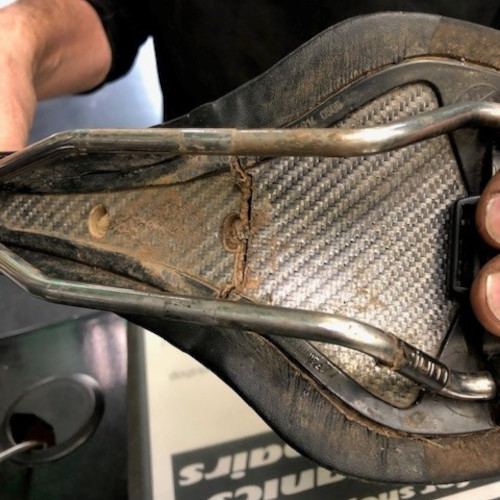 The underside of a bicycle saddle, a large crack across the centre