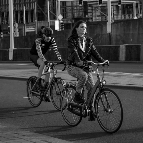 A woman riding a step-through bike along a city street, a male cyclist behind her