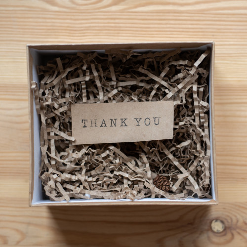 A gift box full of shredded paper with a typed 'THANK YOU' sign nestled inside.