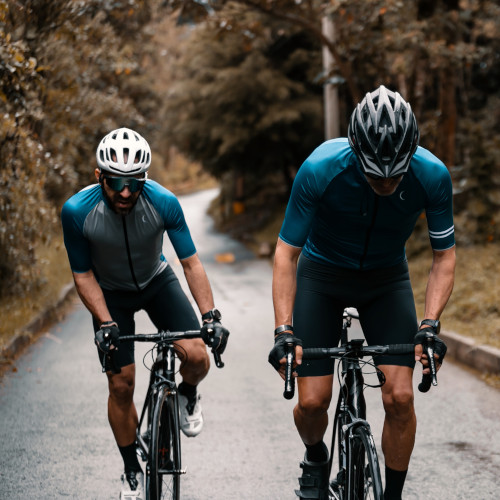 Front-on shot of two road cyclists riding up a rain-slicked incline