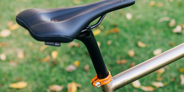 Detail on an SQLab 611 saddle and orange Hope seat clamp fitted to a custom-built Bossi Grit SX titanium gravel bike