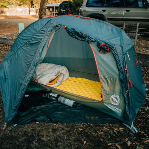 A bikepacking setup for sleeping, with a tent, sleeping pad and sleeping bag.
