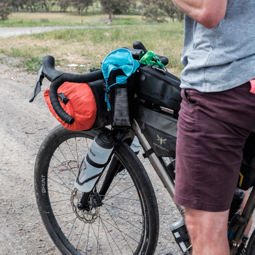 A gravel bike loaded with bikepacking bags, including fork-mounted water bottles.