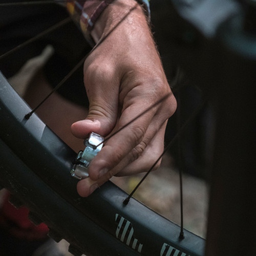 A person using a spoke key tool to tightening a spoke on a mountain bike wheel (close-up of the hand).