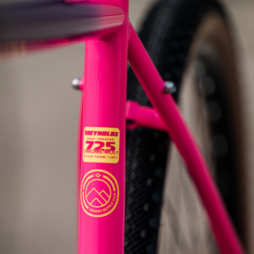 Frame detail on a hot pink Genesis Fugio 30 gravel bike, showing the sticker detailing the chromoly steel of the frame.