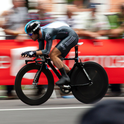 A road cyclist during a time trial, the crowd a blur in the background