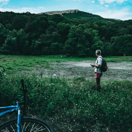 A man surveys an empty field, his bicycle lying in the foreground.