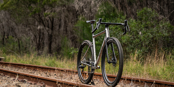 A Bossi Grit SS titanium gravel bike, photographed on deserted train tracks.