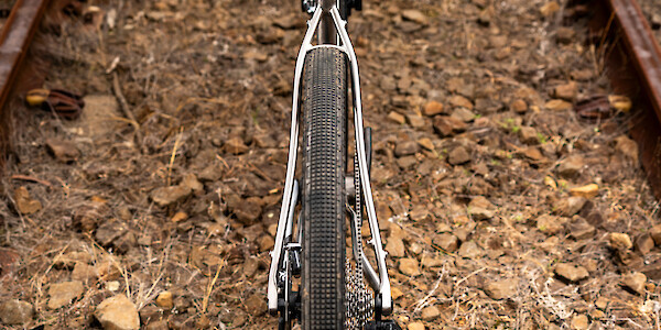 Frame detail on a Bossi Grit SS titanium gravel bike, shot from above against a surface of dirt and gravel.