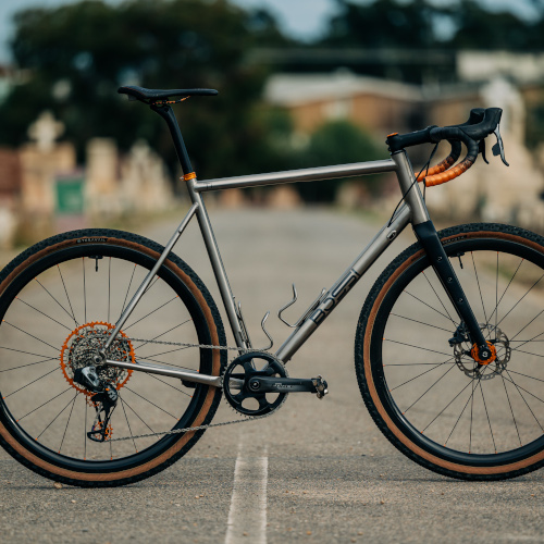 A titanium Bossi gravel bike, fitted with orange Garbaruk components
