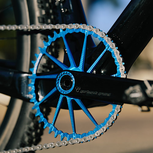 Drivetrain detail of a blue Garbaruk chain ring, fitted to a carbon Gothic Cycles gravel bike