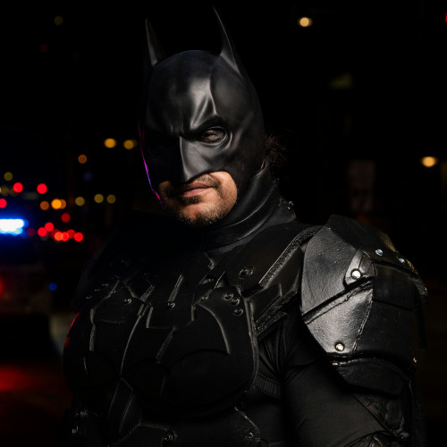 A man in a knockoff Batman costume, looking either sad or defeated.. it's not clear.